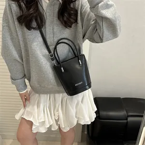 Fashionable black contrast bucket bag for women with white text and adjustable strap