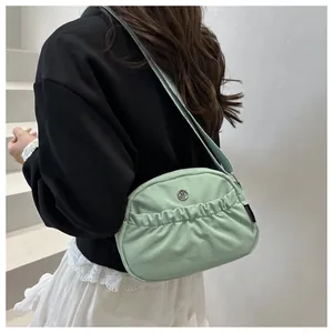 Detail of mint green backpack featuring ruffled pocket and metallic logo on the side