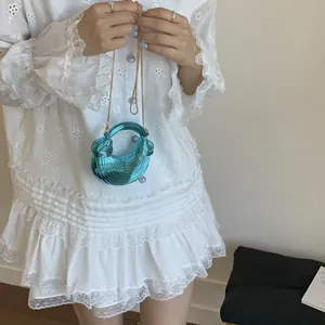 Blue metallic crescent handbag with gold chain strap worn by model in white dress