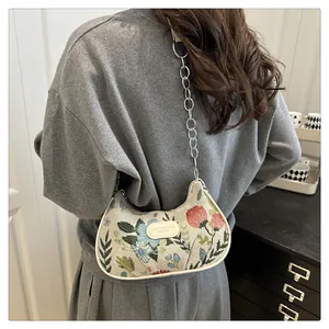 Detailed view of floral embroidery and metallic chain strap on retro underarm bag
