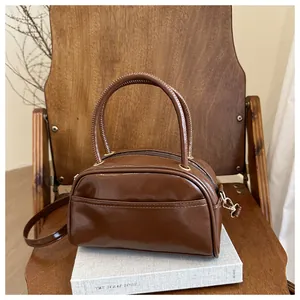 Detail of a brown glossy patent leather pillow bag with a front pocket and sturdy handles
