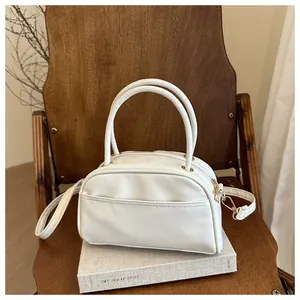 Detail of white semi-oval pillow bag with gold hardware on a vintage wooden chair