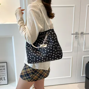 Chic black tote bag with white bow prints and shoulder straps for daily commuting