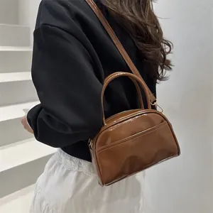 Brown glossy leather Boston pillow bag for women featuring a minimalist retro crossbody design