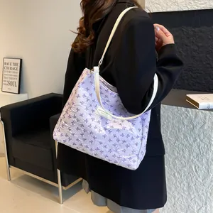 Chic lavender bow-print tote bag with white shoulder straps shown on a model in a studio