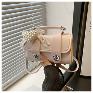 Detalle de bolso bandolera rosa claro con colgante de corazón de perla y lazo