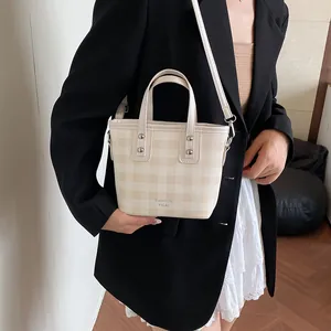 Chic beige and pink checkered mini bucket bag with leather handles and long shoulder strap