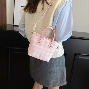 Pink and white checkered bucket bag with dual handles and detachable shoulder strap