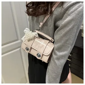 Detalle de bolso rosa claro en charol con lazo de encaje y adornos de perlas de corazón