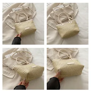 Detailed view of straw woven tote bag featuring leather handles and adjustable shoulder strap