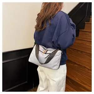 Detail view of a light purple crossbody bag with a wide black strap and orange zip pulls