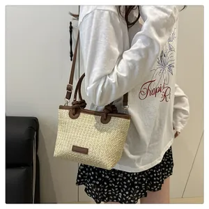 Detailed close-up of a beige straw woven bag with brown leather trim and shoulder strap