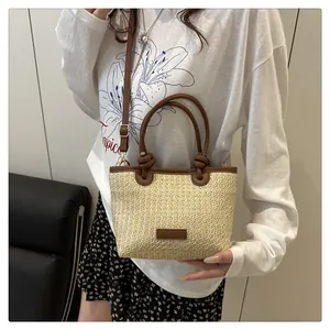 Detail of straw woven tote with brown leather handles and a matching long shoulder strap