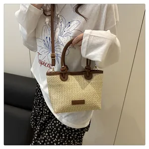 Detail of hand-woven straw tote with brown leather trim and adjustable crossbody strap