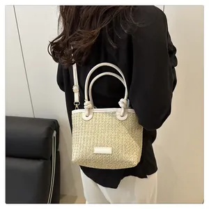 Detail of straw woven tote with white leather handles and knot strap shown with model