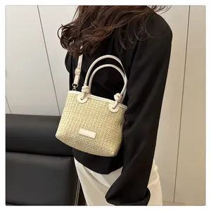 Close-up of woven straw handbag with knotted white leather handles and shoulder strap