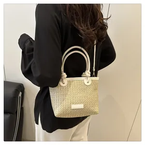 Detail of hand-woven straw tote bag featuring white leather handles and knot accents