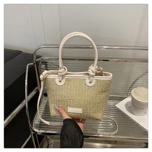 Detail view of woven straw bucket bag with cream faux leather knotted handle and strap
