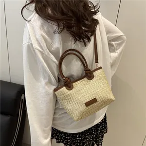 Handwoven straw beach bag with brown leather trim and knotted handles for autumn vacation