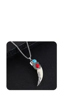 Detail of vintage wolf tooth pendant with blue turquoise inlay and ethnic engraving