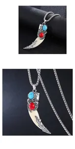 Macro detail of retro wolf tooth pendant with turquoise inlay and silver steel bead chain