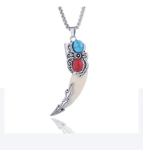 Close-up of vintage wolf tooth pendant with engraved silver and colorful stones