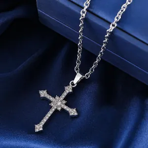 Detailed view of silver cross pendant with sparkling stones on blue silk fabric