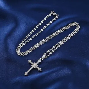 Silver cross necklace with sparkling rhinestones on a premium dark blue satin background