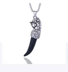 Macro view of silver wolf head carving and black fang pendant on a metal chain