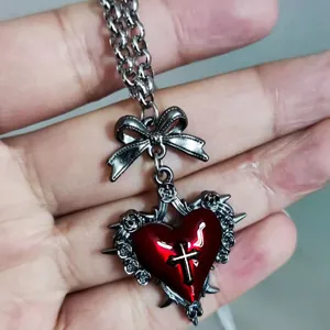 Close-up of gothic necklace featuring dark red heart, cross, and thorn details