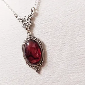 Detailaufnahme des silbernen Vintage-Anhängers mit rotem Harzstein und Schmetterling