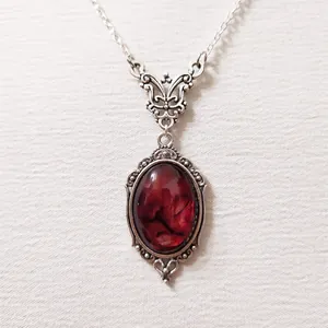 Makroaufnahme der versilberten Vintage-Kette mit rotem ovalem Quarz und Filigran-Details