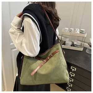 Detail of dark green suede tote bag with slim brown leather strap on model for daily use