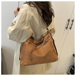Brown suede tote bag with leather straps worn over the shoulder with a beige trench coat