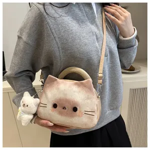 Detail of plush cat crossbody bag featuring embroidered face and bear charm