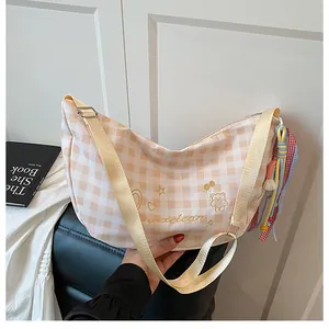 Detalle de bolso de cuadros crema con bordado de oso y colgante de borla tejida