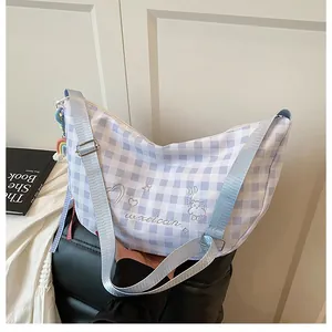 Detalle del bolso de media luna a cuadros azules con bordados y colgante arcoíris