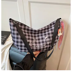 Detalle del bolso bandolera a cuadros blanco y negro con estampado de oso y dije de arcoíris
