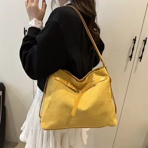 Large yellow suede tote bag with metal grommets worn by a model for a casual commute look