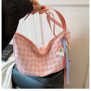 Detalle de bandolera de cuadros rosa con motivos bordados de corazones y osos