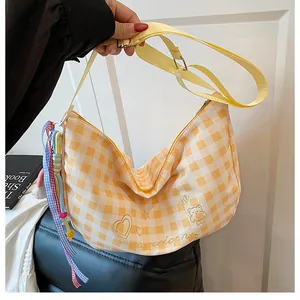 Detalle de bolso bandolera de cuadros amarillos con bordado de oso y colgante de cinta decorativo