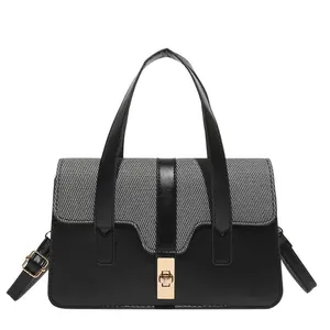 Chic black and gray contrast handbag with gold buckle and adjustable strap on white background