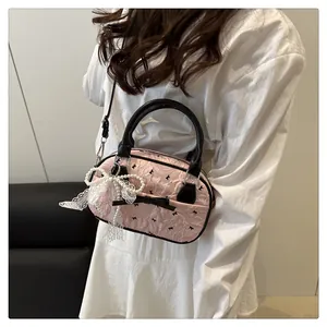Detail of pink Boston bag with black bow print, pearl bow charm and lace decoration