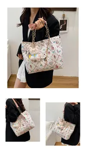 Detail of printed tote bag with cartoon patterns, pink handles and cute rabbit charm