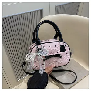 Close-up of pink pleated texture with black bow print and pearl lace charm detail