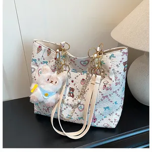 Close-up of a white tote bag featuring cartoon prints, pearl chain, and plush puppy charm