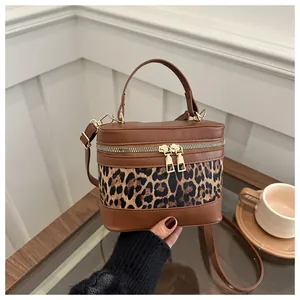 Detail of retro leopard print box bag with golden double zipper on glass table