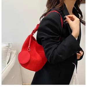 Sac seau rouge en daim avec petit porte-monnaie rond porté avec un blazer noir