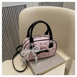 Detail of pink Boston bag with black bow patterns, lace charm and pearl accents