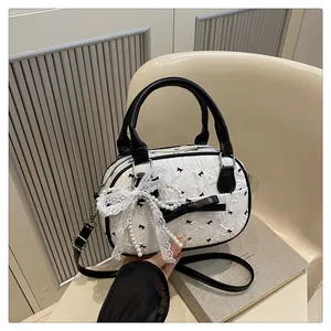 Detail of white textured bowling bag with black bow patterns and pearl lace charms